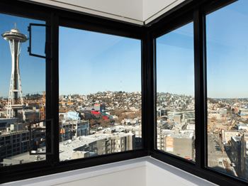 A view of a cityscape from a window with the Space Needle visible in the distance at Skye at Belltown Apartments, Washington 98121